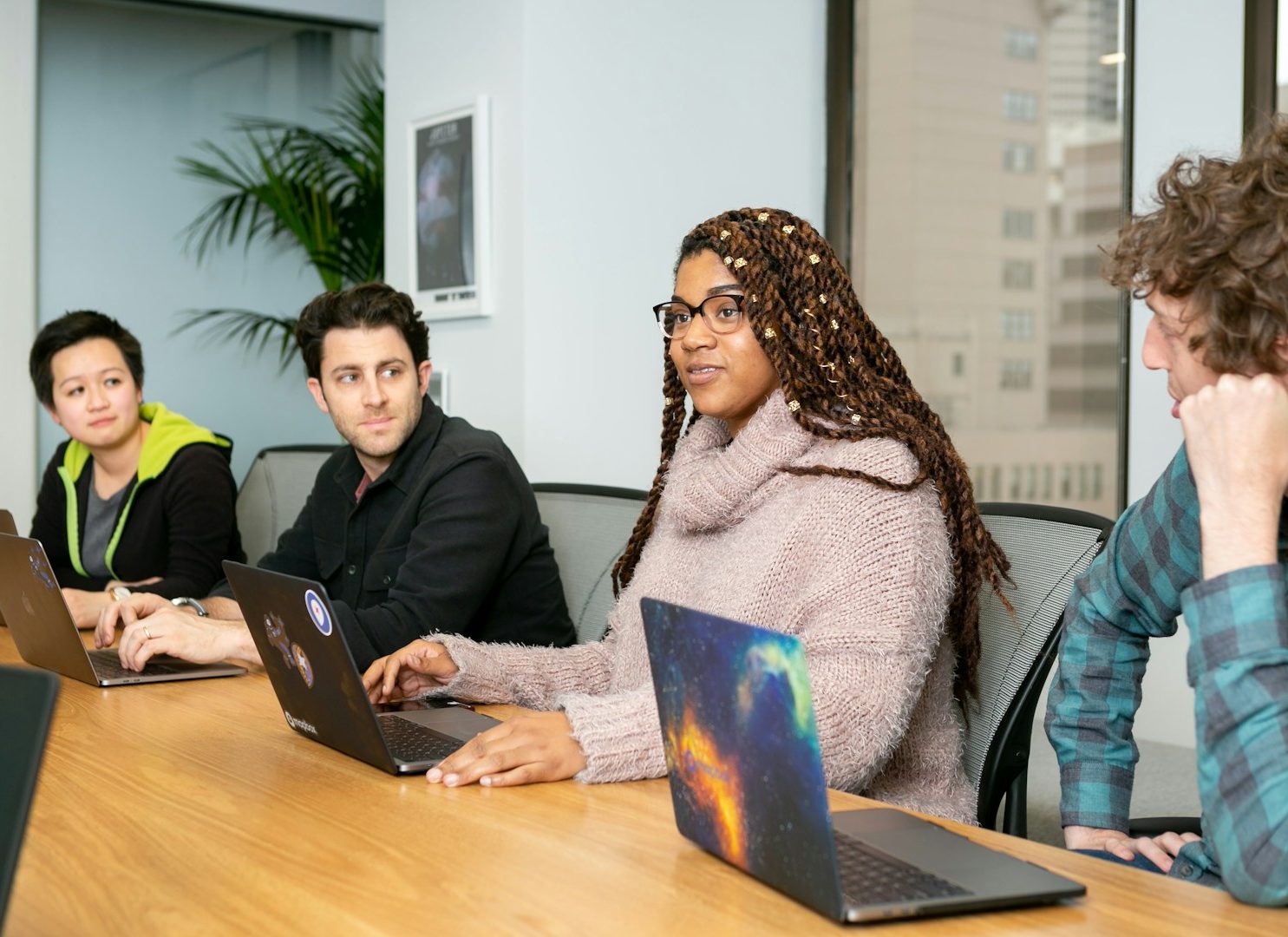 Skill Loop Collective Contact Page Four people sit at a conference table, each using a laptop in a modern office setting.